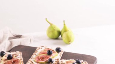 Kanepe veya crostini ile krem peynir ve taze incir dilimleri bir ahşap tahta üzerinde buğday crispread. Lezzetli meze bir aperatif ideal.