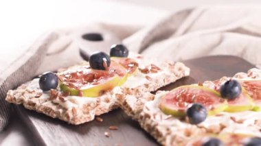 Kanepe veya crostini ile krem peynir ve taze incir dilimleri bir ahşap tahta üzerinde buğday crispread. Lezzetli meze bir aperatif ideal.