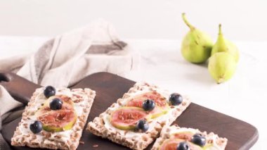 Kanepe veya crostini ile krem peynir ve taze incir dilimleri bir ahşap tahta üzerinde buğday crispread. Lezzetli meze bir aperatif ideal.