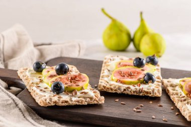 Kanepe veya crostini ile krem peynir ve taze incir dilimleri bir ahşap tahta üzerinde buğday crispread. Lezzetli meze bir aperatif ideal.