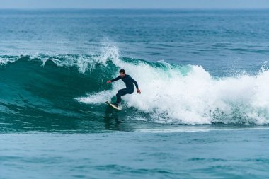 Bulutlu bir günde okyanus dalgaları üzerinde eylem sörfçü.