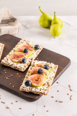 Kanepe veya crostini ile krem peynir ve taze incir dilimleri bir ahşap tahta üzerinde buğday crispread. Lezzetli meze bir aperatif ideal.
