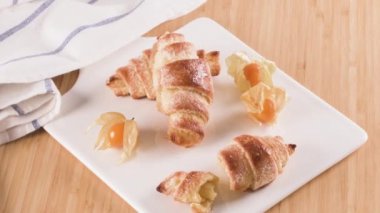 Küçük ayçöreği beyaz seramik tepsi içinde physalis meyve, ahşap masa üstüne ev yapımı kekler.