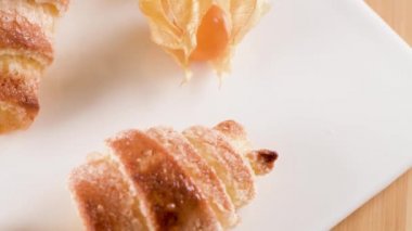 Küçük ayçöreği beyaz seramik tepsi içinde physalis meyve, ahşap masa üstüne ev yapımı kekler.