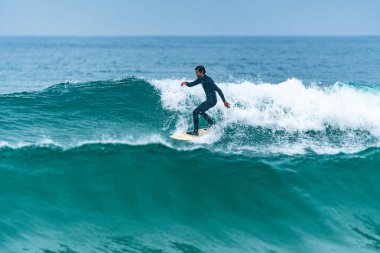 Bulutlu bir günde okyanus dalgaları üzerinde eylem sörfçü.