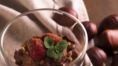 Çikolata ve kestane mousse kavrulmuş badem ve yulaf ile kadeh ahududu ile dekore edilmiş ve nane yaprakları.