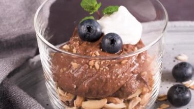 Cam bardak çikolata ve kestane mousse kavrulmuş badem ve yulaf ile dekore edilmiş ile siyah çilek ve nane yaprakları.