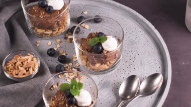 Cam bardak çikolata ve kestane mousse kavrulmuş badem ve yulaf ile dekore edilmiş ile siyah çilek ve nane yaprakları.
