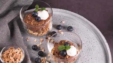 Cam bardak çikolata ve kestane mousse kavrulmuş badem ve yulaf ile dekore edilmiş ile siyah çilek ve nane yaprakları.