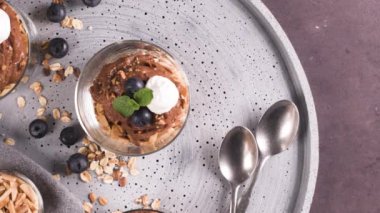 Cam bardak çikolata ve kestane mousse kavrulmuş badem ve yulaf ile dekore edilmiş ile siyah çilek ve nane yaprakları.