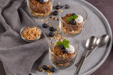 Cam bardak çikolata ve kestane mousse kavrulmuş badem ve yulaf ile dekore edilmiş ile siyah çilek ve nane yaprakları.