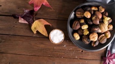 Rustik ahşap tahta ve gri ahşap arka plan, seçici odak üzerinde kavrulmuş kestane dökme demir tava.