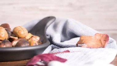 Rustik ahşap tahta ve gri ahşap arka plan, seçici odak üzerinde kavrulmuş kestane dökme demir tava.