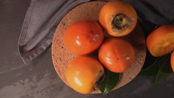 Rijpe Kaki Fruit Een Bord Van Kurk Tegenbovenkant Donkere Keuken — Stockvideo