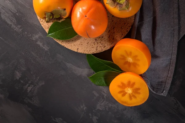 Rijpe Kaki Fruit Een Bord Van Kurk Tegenbovenkant Donkere Keuken — Stockfoto