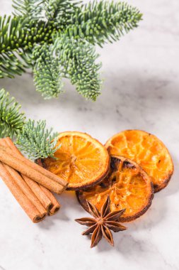 Dilim kurutulmuş portakal ve mermer yüzeyindeki çam dalı.