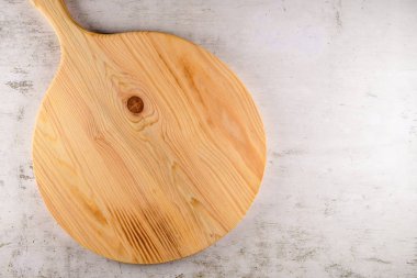 Yuvarlak ahşap kesme tahtası (pizza tahtası) parlak gri taş zemin üzerinde. Metin için yer kopyalayın.
