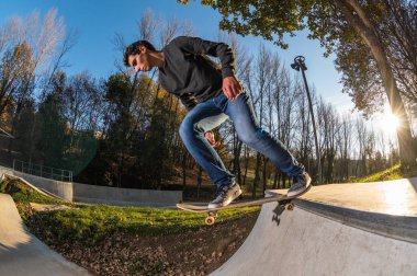 Kaykaycı dropring bir rampa yerel skatepark, gün batımında.