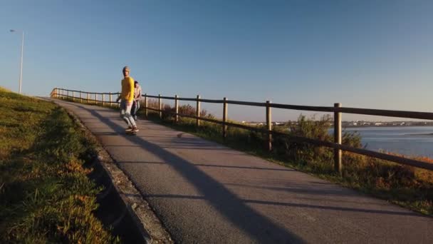 Gördeszkázók Cirkál Gyalogos Séta Folyó Naplementekor — Stock videók