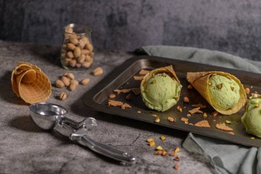 Siyah bir arka planda waffle konileri fıstık dondurması topları.