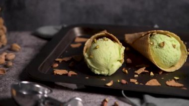 Siyah bir arka planda waffle konileri fıstık dondurması topları.