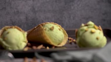 Siyah bir arka planda waffle konileri fıstık dondurması topları.