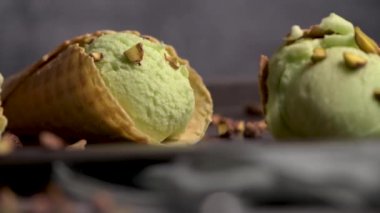 Siyah bir arka planda waffle konileri fıstık dondurması topları.