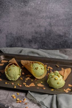 Siyah bir arka planda waffle konileri fıstık dondurması topları.