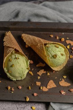 Siyah bir arka planda waffle konileri fıstık dondurması topları.