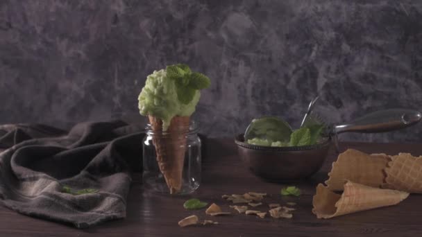 茶色の木製の背景に暗い素朴なボウルとワッフルコーンのピスタチオアイスクリーム — ストック動画