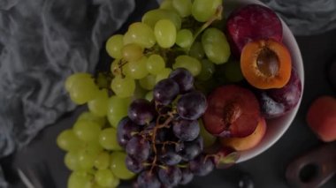 Meyve Beyaz seramik kase meyve ile yaşam. Beton duvar. Dramatik ışık. Üzüm, kayısı ve erik.