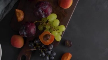 Meyve Beyaz seramik kase meyve ile yaşam. Beton duvar. Dramatik ışık. Üzüm, kayısı ve erik.