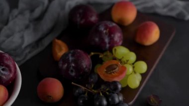 Meyve Beyaz seramik kase meyve ile yaşam. Beton duvar. Dramatik ışık. Üzüm, kayısı ve erik.