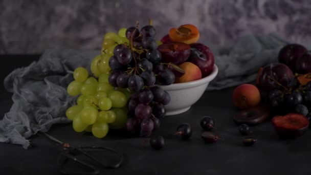 Fruchtstillleben Mit Früchten Auf Weißer Keramikschale Betonmauer Dramatisches Licht Trauben — Stockvideo