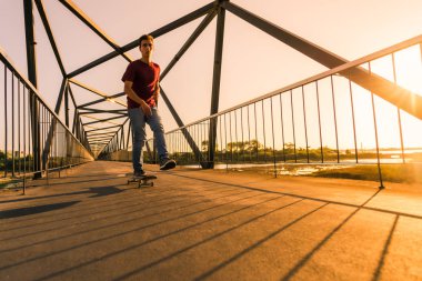 Gün batımında köprüde genç kaykaycı