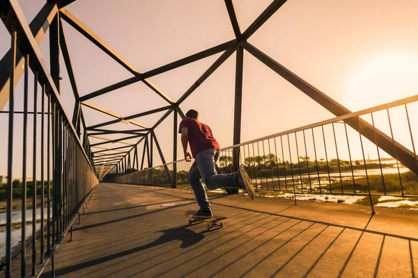 Gün batımında köprüde genç kaykaycı — Stok fotoğraf