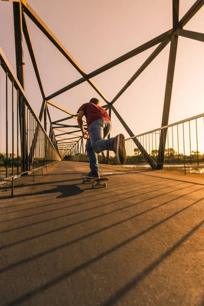 Gün batımında köprüde genç kaykaycı