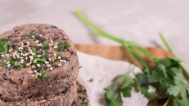 Ahşap kesme tahtası üzerinde maydanoz yaprakları ile siyah fasulye ile Çiğ vejetaryen burger.