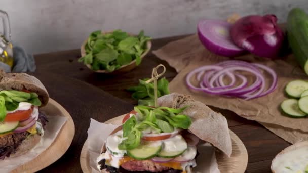 新鮮な野菜とヨーグルトソースと健康的なビーガンバーガー素朴なキッチンカウンターの上に — ストック動画