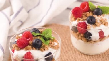 Granola böğürtlen ve ahududu. Açık beyaz ahşap arka planda ev yapımı yoğurt. Sağlıklı gıda konsepti.