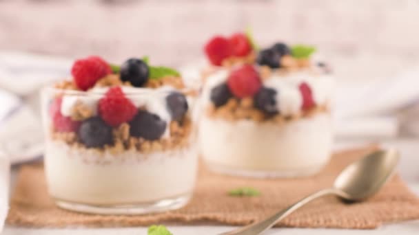 格拉诺拉黑莓和覆盆子自制的酸奶在浅白的木制背景玻璃 健康食品概念 — 图库视频影像