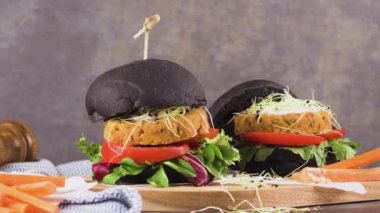 Lezzetli ızgara vejetaryen burgerler nohut ve siyah ekmeğin üstünde sebzeler ve ahşap tezgah..