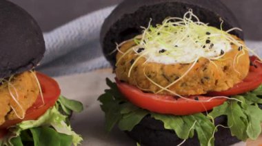 Lezzetli ızgara vejetaryen burgerler nohut ve siyah ekmeğin üstünde sebzeler ve ahşap tezgah..