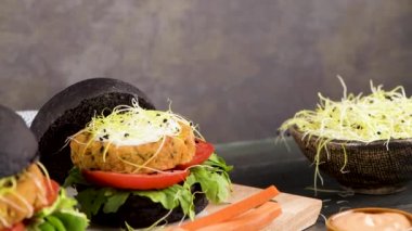 Lezzetli ızgara vejetaryen burgerler nohut ve siyah ekmeğin üstünde sebzeler ve ahşap tezgah..