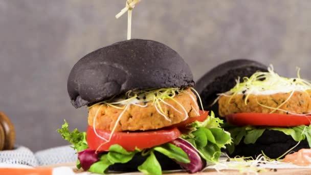 濃い木のカウンターの上に黒パンにひよこ豆や野菜とおいしい焼き野菜バーガー — ストック動画