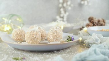 Hindistan cevizi kavrulmuş bademli ev yapımı şekerler. Işıklar ve yıldızlarla süslenmiş bir Noel masasında..
