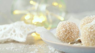 Hindistan cevizi kavrulmuş bademli ev yapımı şekerler. Işıklar ve yıldızlarla süslenmiş bir Noel masasında..