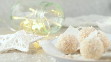 Hindistan cevizi kavrulmuş bademli ev yapımı şekerler. Işıklar ve yıldızlarla süslenmiş bir Noel masasında..