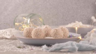 Hindistan cevizi kavrulmuş bademli ev yapımı şekerler. Işıklar ve yıldızlarla süslenmiş bir Noel masasında..