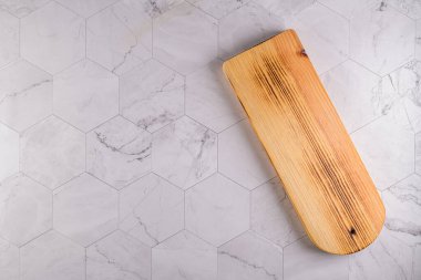 Modern altıgen desenli mermer taş tezgahın ahşap kesim tahtasının üst görüntüsü.